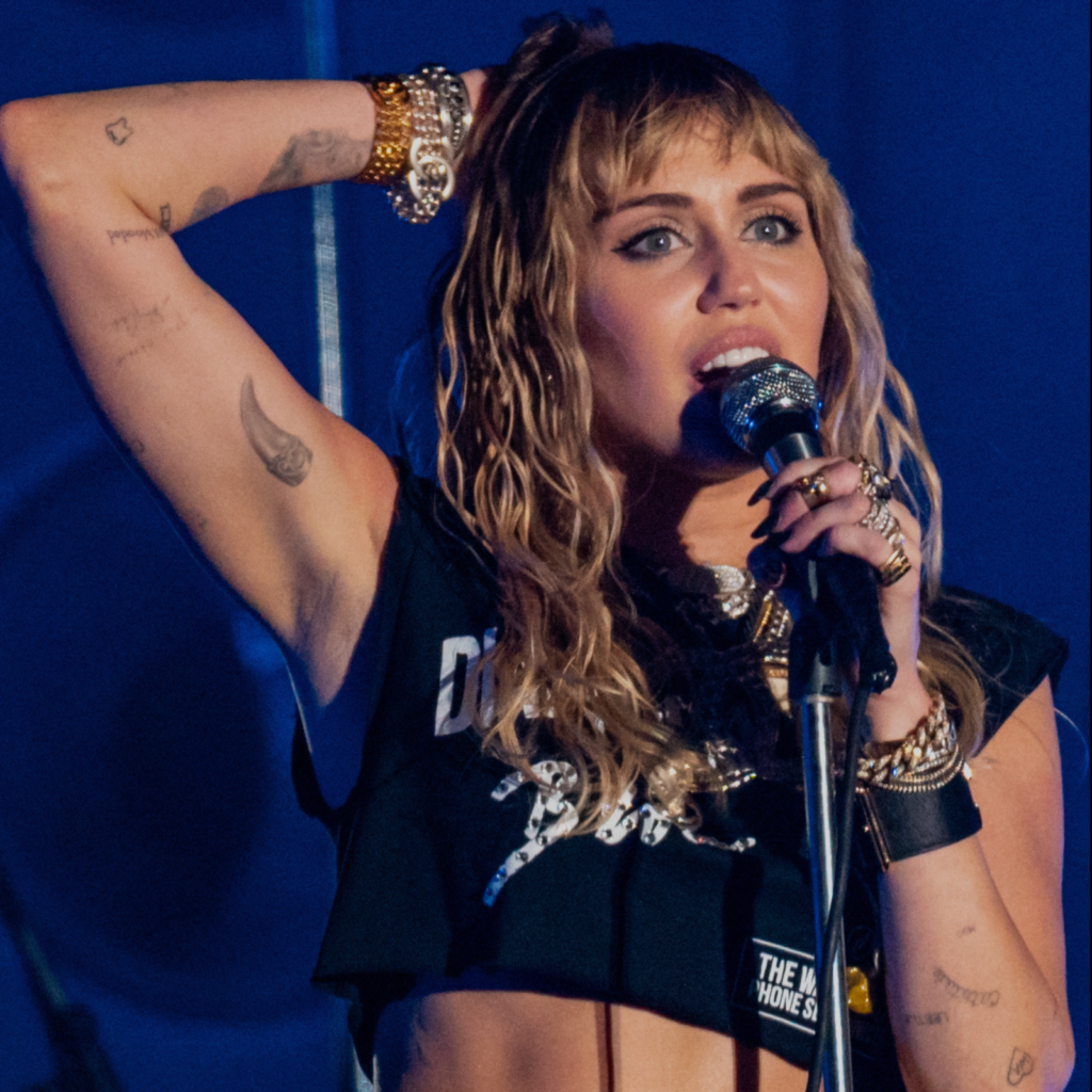 Miley Cyrus cantando em um show, representando a energia da Autoridade Emocional no Desenho Humano